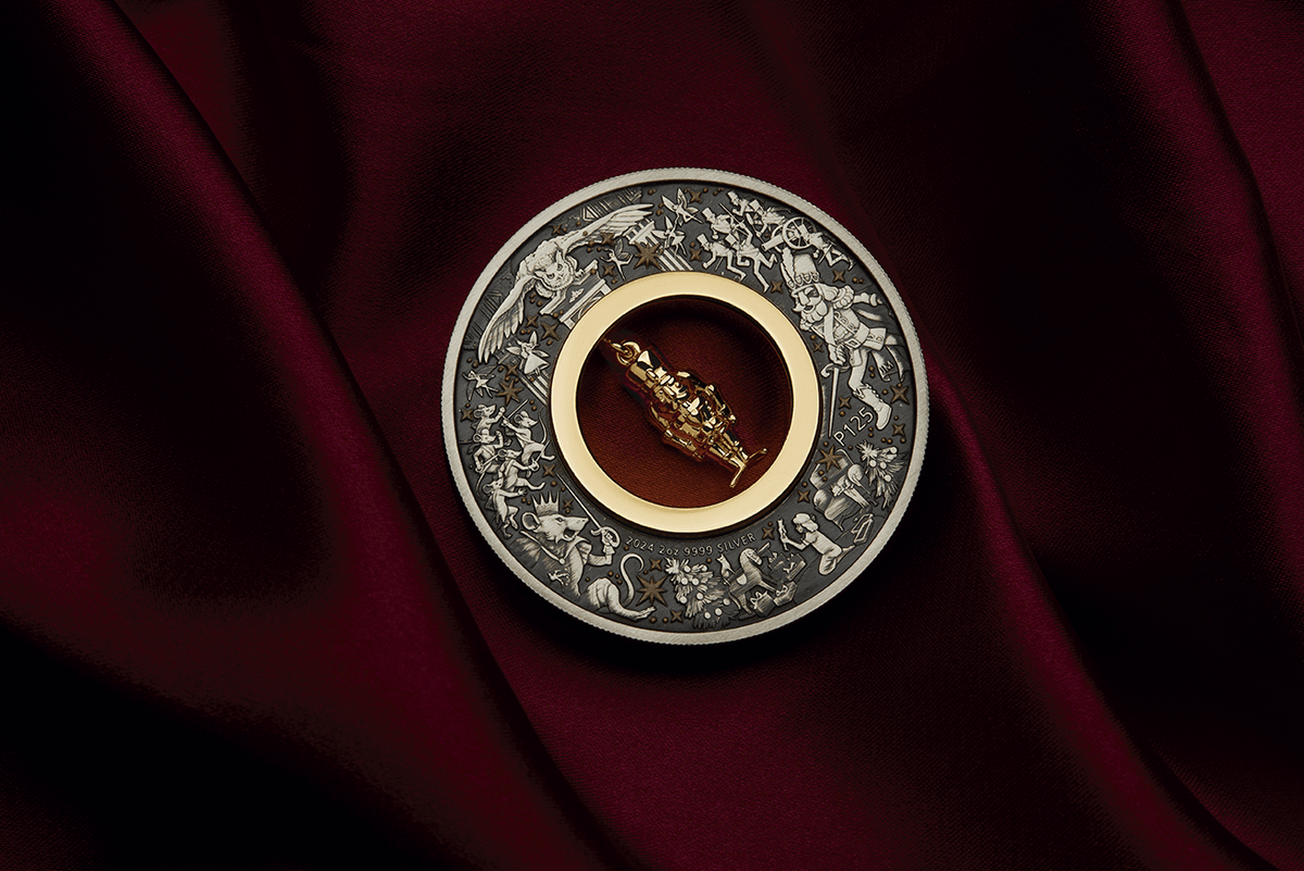 Christmas Nutcracker silver coin on burgundy fabric with its central gold-plated figurine tilted diagonally