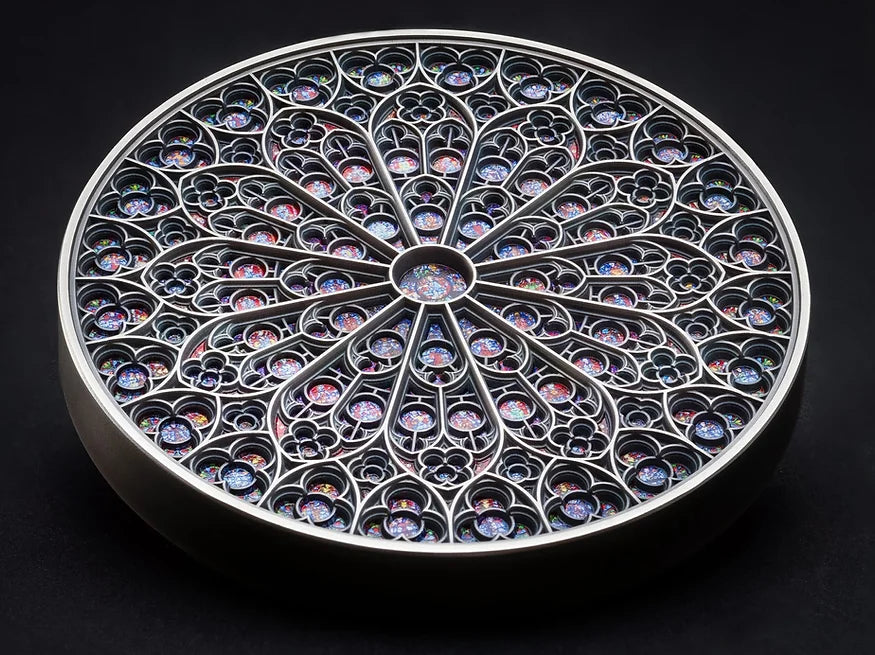 The Fiji 2024 Notre Dame 5 oz Silver Special Edition Coin lies Flat on a dark surface. The coin is a colorful mandala art design featuring intricate patterns and the Notre-Dame cathedral iconic rose window reproduction.