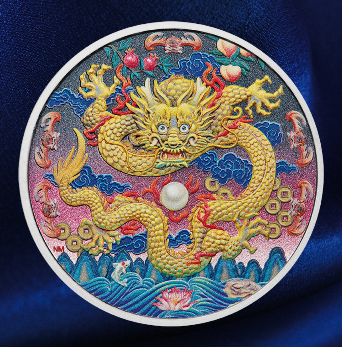 A circular collectible coin featuring a detailed Chinese dragon design, displayed on a dark blue satin fabric background. The coin has a white border and is decorated with a golden dragon, blue clouds, red fruits, and a white pearl-like center.