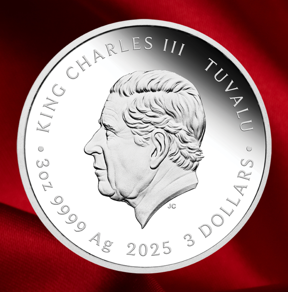A round silver coin featuring a profile portrait of King Charles III of Tuvalu, with engraved text reading 'KING CHARLES III TUVALU' and '3 DOLLARS 9999 Ag 2025'. The coin is photographed against a rich red fabric background.