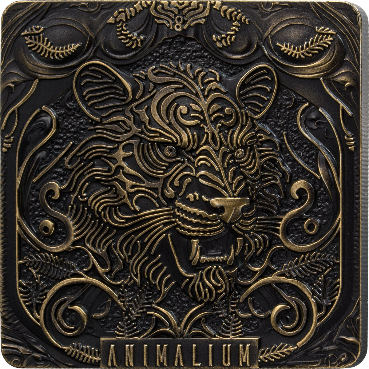 A square decorative plaque or box cover featuring an ornate embossed animal head with swirling floral and scroll motifs, in dark metallic black and antique gold tones. The word 'ANIMALIUM' appears at the bottom.
