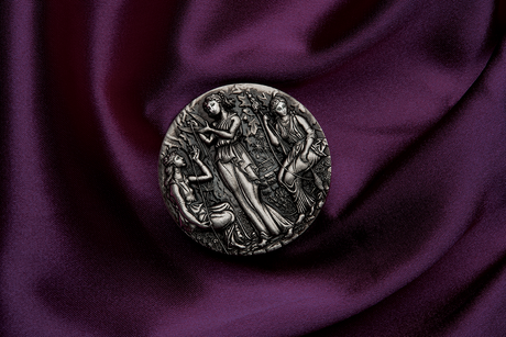 A silver coin with a detailed relief design featuring three ancient goddesses, Clotho, Lachesis, and Atropos, from Greek mythology, within a grove setting. The Coin is in a setting of luxurious purle velvet lying flay giving a birdseye view. The coin is rotated to 11 o'clock.