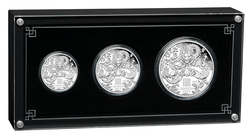 Three silver coins in a black display case with decorative elements.