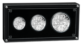 Three silver coins in a black display case with decorative elements.