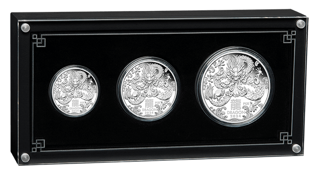 Three silver coins in a black display case with decorative elements.