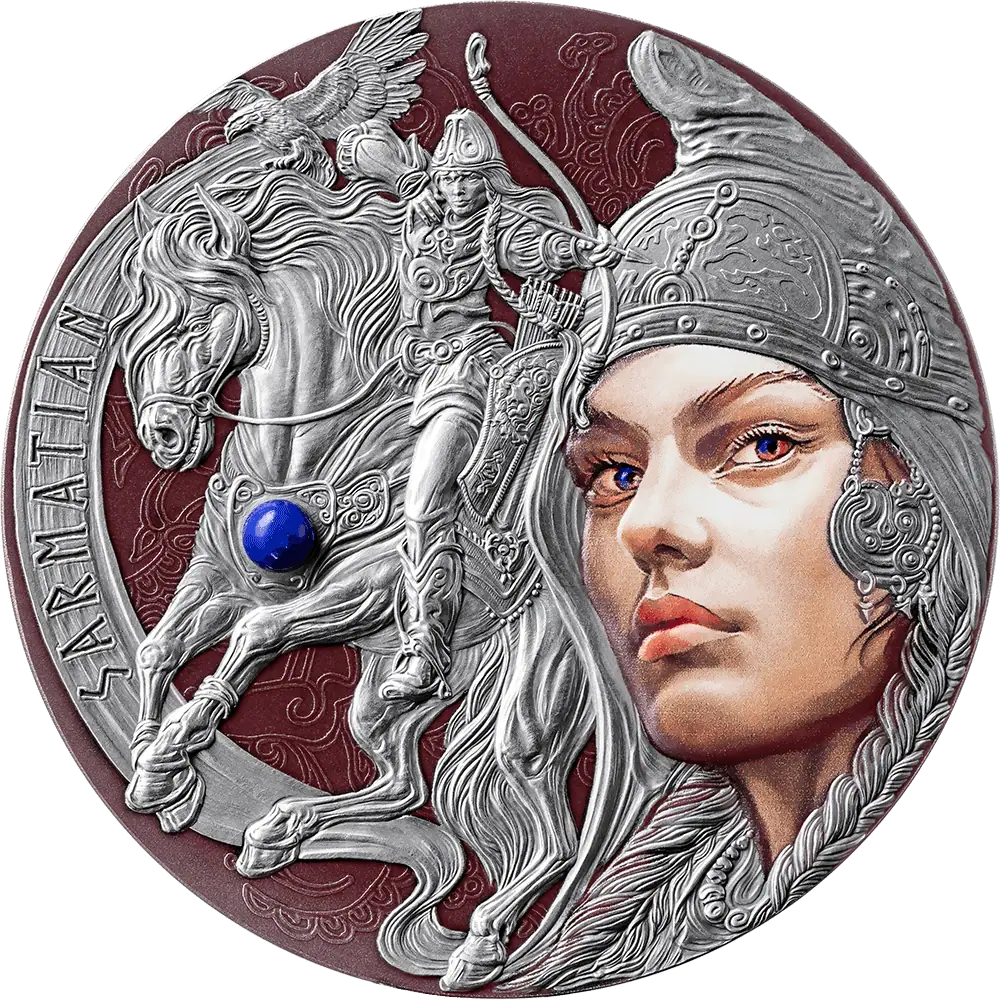 A circular silver-toned medallion or coin featuring a sculpted warrior on a horse with a winged motif, alongside a large stylized female face in profile. The design includes embossed details, engraved text along the left edge, and a small blue gemstone accent on the horse.