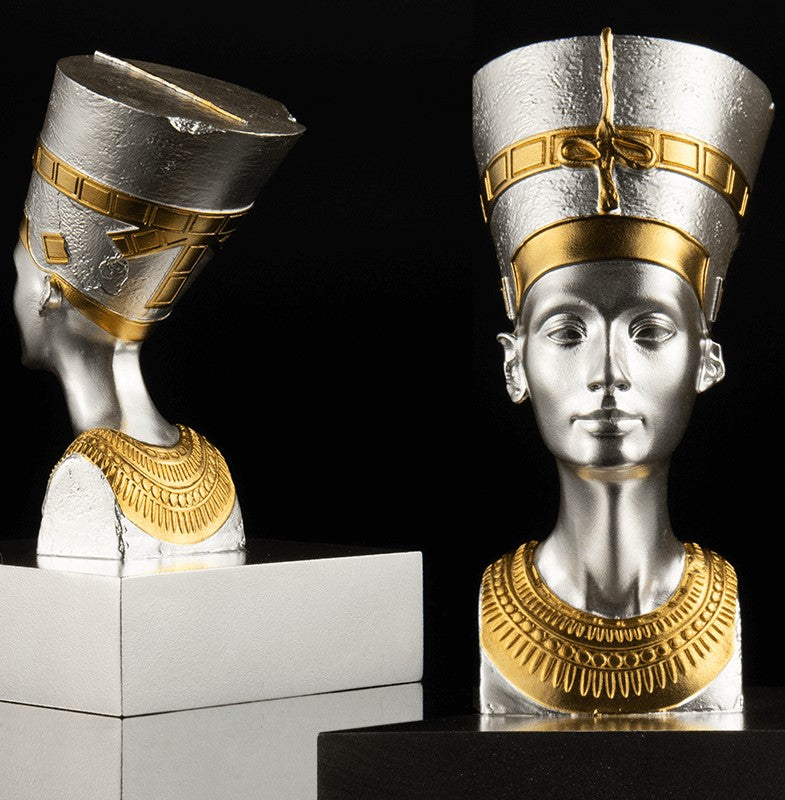 A 3D shaped silver coin with gold gilding, depicting the bust of Nefertiti. The coin is displayed on a stand against a black background.