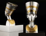 The Bust of Nefertitishowing ehind and front view of a 3D shaped silver coin with gold gilding, depicting the bust of Nefertiti. The coin is displayed on a stand against a black background.