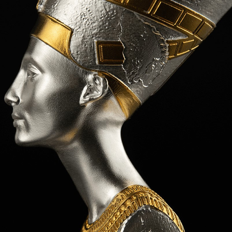 Sideview or Profile of a 3D shaped silver coin with gold gilding, depicting the bust of Nefertiti. The coin is displayed on a stand against a black background.