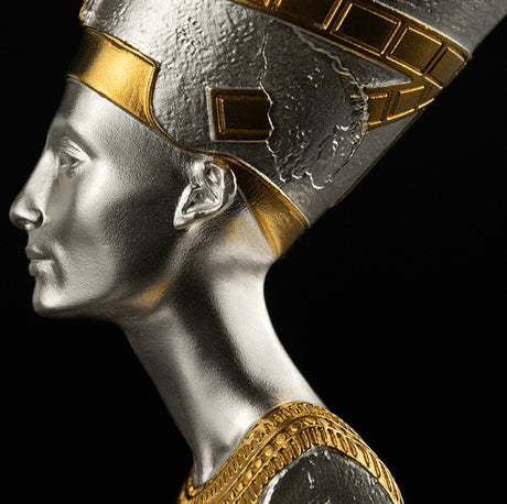 Sideview or Profile of a 3D shaped silver coin with gold gilding, depicting the bust of Nefertiti. The coin is displayed on a stand against a black background.