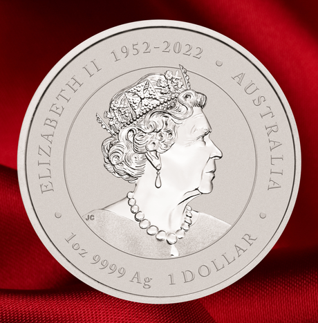 A round silver commemorative coin featuring a profile portrait of Queen Elizabeth II, with engraved text reading 'ELIZABETH II 1952-2022', 'AUSTRALIA', '1oz 9999 Ag', and '1 DOLLAR'. The coin is photographed close-up against a rich red satin fabric background.