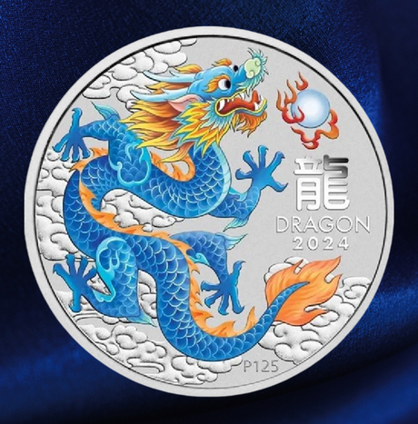 A round silver commemorative coin featuring a detailed blue dragon with orange and yellow accents, set against a dark blue textured fabric background. The coin includes the text 'DRAGON 2024' and 'P125'.