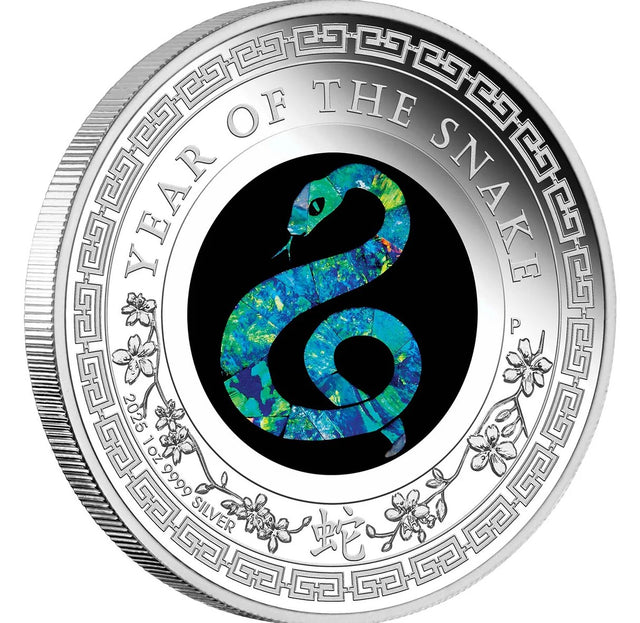 Silver coin with Year of the Snake design in opal on a black background