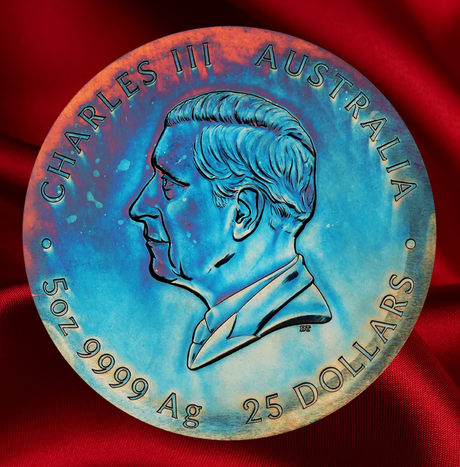A circular collectible coin or medallion featuring a profile portrait of Charles III of Australia, with 'CHARLES III AUSTRALIA' and '50Z 9999 Ag 25 DOLLARS' inscribed around the edge, displayed on a red satin fabric background.
