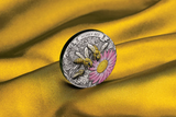 Decorative coin with honey bee and flower design on a yellow fabric background