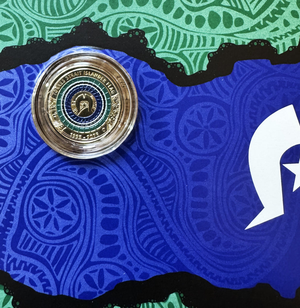 Torres Strait Islander Flag Coin with C Mintmark on a blue and green flag patterned Card Detail.