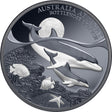A collectible coin featuring a design of a mother and her calf bottlenose dolphin with a Black Proof finish, accompanied by marine life and the Moonlit black sky in the background.