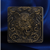 A square decorative plaque or box with an embossed lion face and ornate scrollwork, finished in dark metallic bronze with gold highlights, set against a deep blue satin background. The word 'ANIMALLIUM' appears at the bottom.
