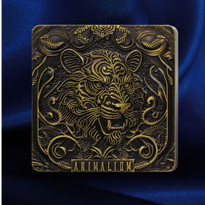 A square decorative plaque or coin featuring an ornate embossed tiger head and scrollwork, with the word 'ANIMALLIUM' at the bottom, shown against a deep blue satin-like background.