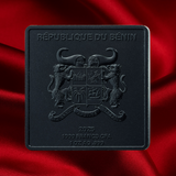 A square black commemorative coin or medallion embossed with the Republic of Benin coat of arms and text reading '2025 1000 FRANCS CFA 1 OZ AG .999', photographed against draped red satin fabric.