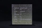 Silver coin in a protective case with embossed text on a black background