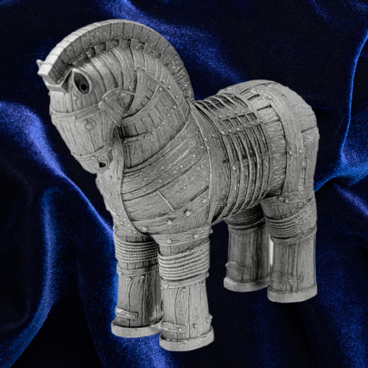 A miniature gray resin figurine of the Trojan Horse, shown against a draped dark blue velvet background.