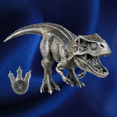 Tyrannosaurus rex three-dimensional silver coin with open jaws beside its footprint-shaped obverse against blue satin.