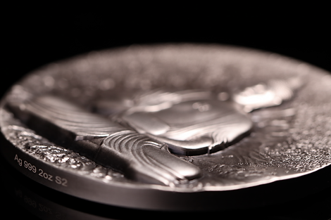 Close-up of a silver coin with detailed  Buddha design on a black background