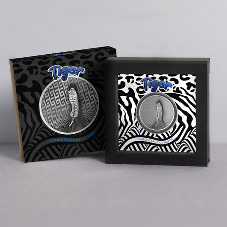Tiger Camouflage of Nature silver coin in a black presentation stand beside its tiger-patterned outer packaging.