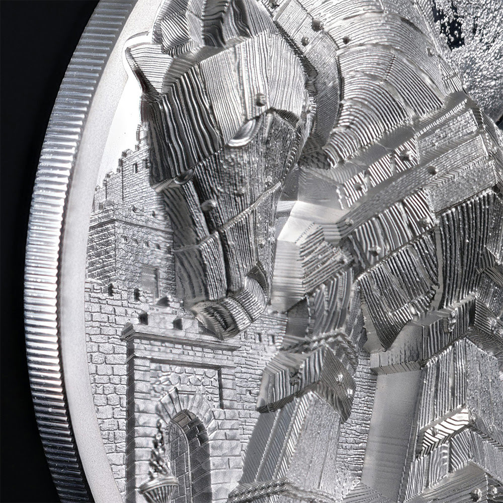 Close-up of a silver-toned coin or medallion featuring an intricate relief design of a horse and castle, with a ribbed circular edge visible against a dark background.