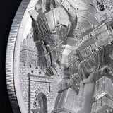 Close-up of a silver-toned coin or medallion featuring an intricate relief design of a horse and castle, with a ribbed circular edge visible against a dark background.