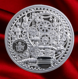 A circular silver collectible coin featuring intricate steampunk gear and cogs, with a black inset showing the Cook Islands emblem and text. The coin is photographed on a rich red satin fabric background.