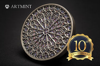 A Gold and Blue 1`0th Anniversary badge is pinned to a mood photo of a Mandala coin. The coin depicts a colorful mandala art design featuring intricate patterns and the Notre-Dame cathedral iconic rose window reproduction.