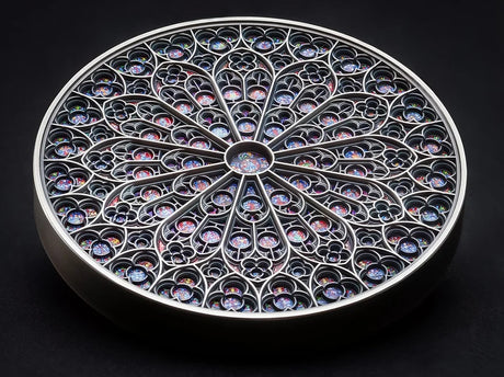 The Fiji 2024 Notre Dame 5 oz Silver Special Edition Coin lies Flat on a dark surface. The coin is a colorful mandala art design featuring intricate patterns and the Notre-Dame cathedral iconic rose window reproduction.