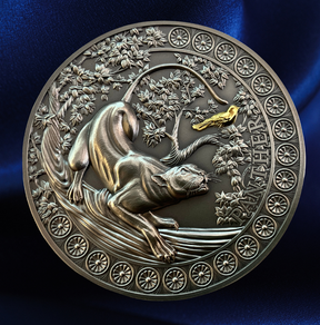 A round metallic medallion or coin featuring an embossed animal and floral design, photographed against a dark blue satin-like background. The piece appears silver-toned with a small gold accent near the top right.