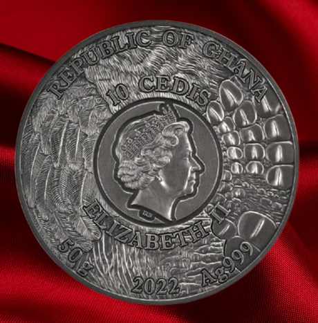A circular silver-colored commemorative coin of the Republic of Ghana, featuring Queen Elizabeth II and the denomination '10 Cedis' in raised relief, displayed on a draped red fabric background.