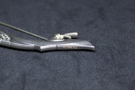 Close-up of a silver Crescent Bow on a dark fabric background