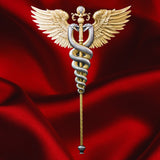 KOMSCO 2025 Winged Staff silver stacker with gilded wings and entwined silver serpents, displayed against red satin.