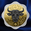 A 5 Euro coin featuring a detailed black bull head on a gold background with decorative swirls and a silver-toned scalloped border, set against a dark blue satin fabric backdrop.