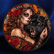A circular decorative coin or medallion featuring a Day of the Dead-style woman with sugar skull makeup, red roses, black lace clothing, a black panther, and Spanish text reading '1 ONZA PLATA PURA 2024 999' and 'LEY 999'. The plaque is photographed against a dark blue satin-like background.
