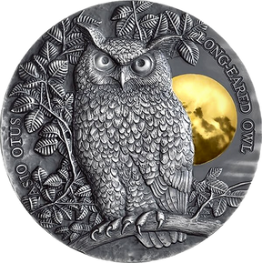 A high relief design of a long-eared owl perched above a gilded moon on a silver coin, with leaves and branches in the background.