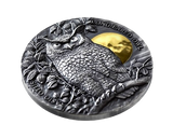 Silver coin with an owl and gold plated moon design on a white background showing also its smooth Rim.