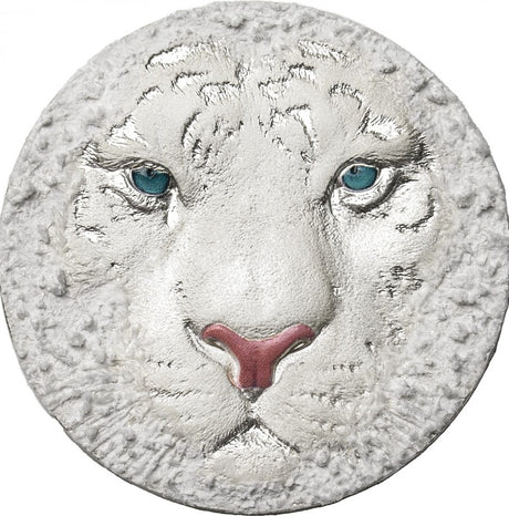A silver coin with a high relief design depicting the head of a white tiger.
