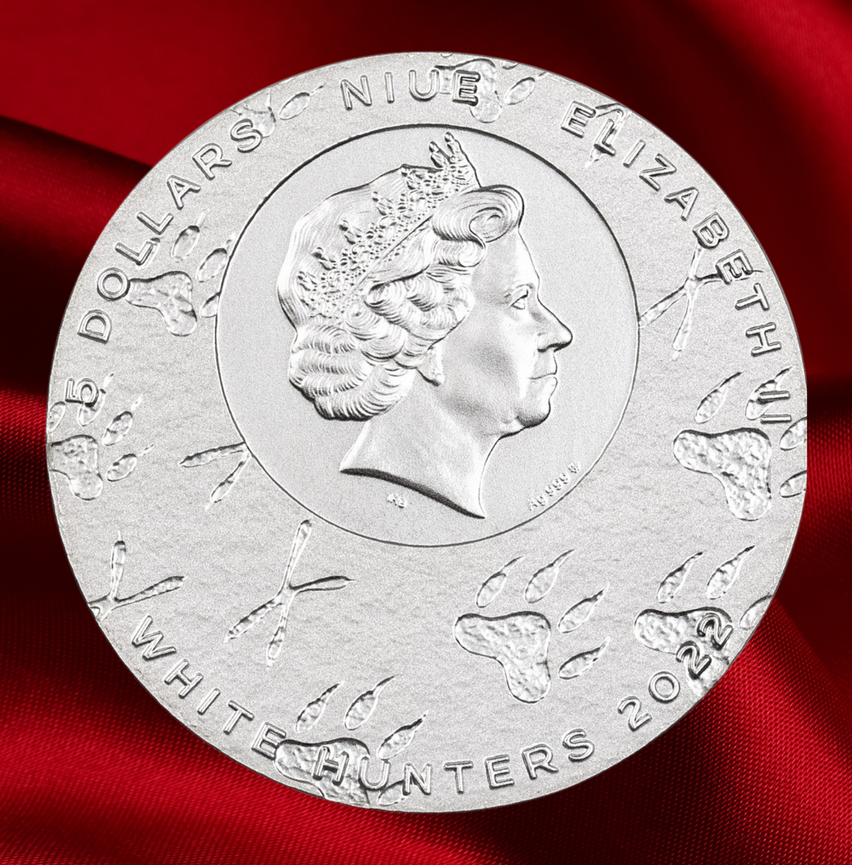 A round silver commemorative coin featuring a profile portrait of Queen Elizabeth II, with engraved text reading 'FIVE DOLLARS NIUE ELIZABETH' and 'WHITE HUNTERS 2023', displayed on a rich red fabric background.