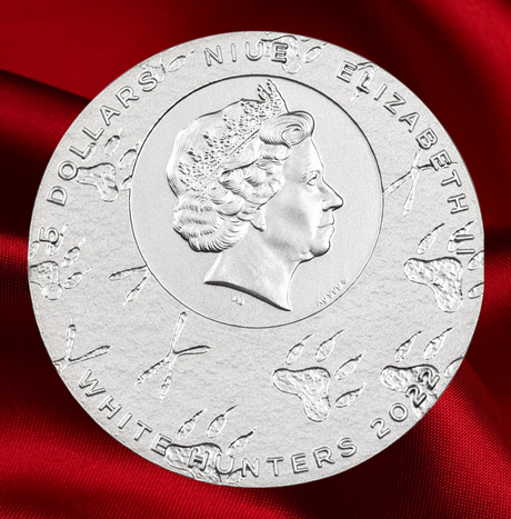 A round silver commemorative coin featuring a profile portrait of Queen Elizabeth II, with engraved text reading 'FIVE DOLLARS NIUE ELIZABETH' and 'WHITE HUNTERS 2023', displayed on a rich red fabric background.