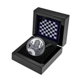 Silver coin in a black box with a checkered pattern on a white background