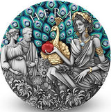 The image on the coin shows Hera with a peacock. Hera is feeding the peacock a pomegranate and the Peacocks feathers are in display with Aquamarine Crystal inserts. To the left is a pregnant woman and a man. The Peacock Body is gilded. His feathers are coloured. Flowers populate the foreground in antiqued silver. 23 sparkling Aquamarine Crystals adorn the feathers.  White background small shadow at base of standing coin.