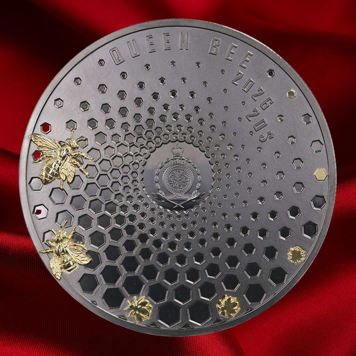 A round dark metallic coin or featuring a honeycomb pattern, embossed text reading 'QUEEN BEE' and '2026 20$', two gold-tone bees on the left, and two small gold bees birthing  from the comb. Background is white.