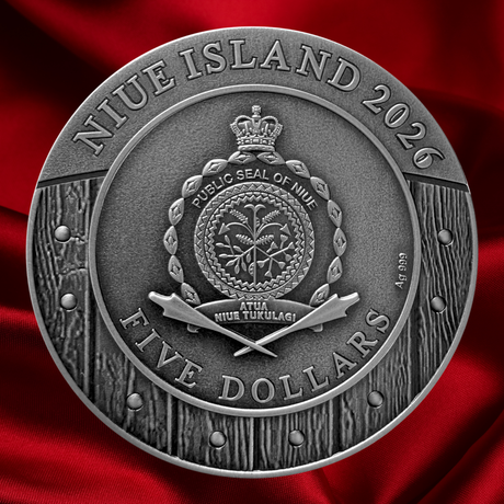A round silver-toned commemorative coin or medallion reading 'NIUE ISLAND 2026' and 'FIVE DOLLARS,' with the Public Seal of Niue in the center, shown against a draped red satin background.