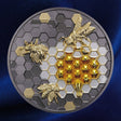 A circular collectible coin featuring a gold and silver honeycomb design with three gold bees, isolated on a white background.